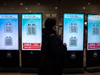 A women walks pass monitor displaying Leave Home Safe QR Code on December 13, 2022 in Hong Kong, China. The Hong Kong Government announced t...