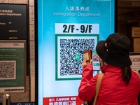 A women scanning a Leave Home Safe QR code display on a screen on December 13, 2022 in Hong Kong, China. The Hong Kong Government announced...