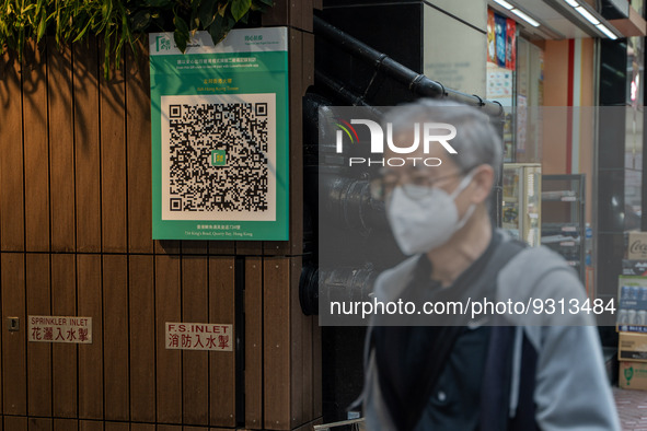 A man walks pass a Leave Home Safe QR code placed on the wall on December 13, 2022 in Hong Kong, China. The Hong Kong Government announced t...