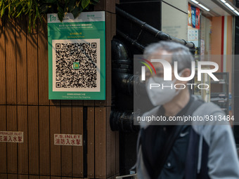 A man walks pass a Leave Home Safe QR code placed on the wall on December 13, 2022 in Hong Kong, China. The Hong Kong Government announced t...