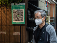 A man walks pass a Leave Home Safe QR code placed on the wall on December 13, 2022 in Hong Kong, China. The Hong Kong Government announced t...