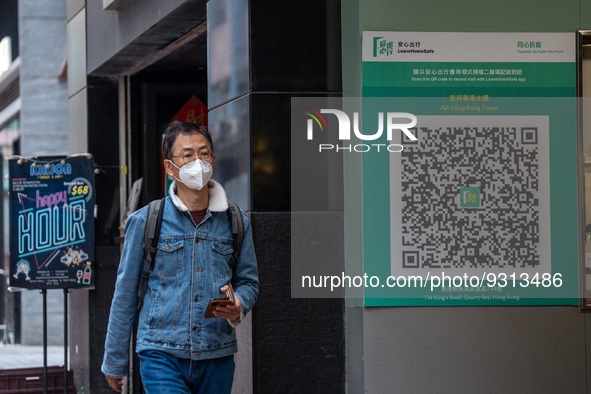 A man walks pass a Leave Home Safe QR code placed on the wall on December 13, 2022 in Hong Kong, China. The Hong Kong Government announced t...