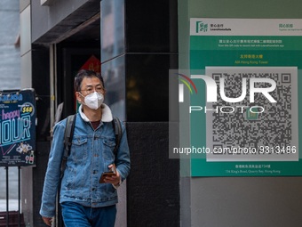 A man walks pass a Leave Home Safe QR code placed on the wall on December 13, 2022 in Hong Kong, China. The Hong Kong Government announced t...