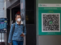 A man walks pass a Leave Home Safe QR code placed on the wall on December 13, 2022 in Hong Kong, China. The Hong Kong Government announced t...