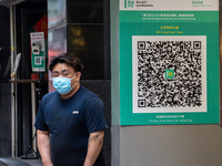 A man walks pass a Leave Home Safe QR code placed on the wall on December 13, 2022 in Hong Kong, China. The Hong Kong Government announced t...