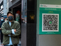 A men walks pass a Leave Home Safe QR Code place on the wall on December 13, 2022 in Hong Kong, China. The Hong Kong Government announced th...