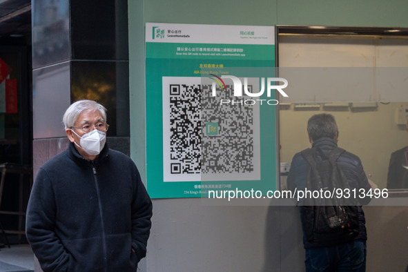 A man walks pass a Leave Home Safe QR code placed on the wall on December 13, 2022 in Hong Kong, China. The Hong Kong Government announced t...