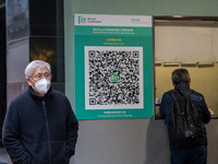 A man walks pass a Leave Home Safe QR code placed on the wall on December 13, 2022 in Hong Kong, China. The Hong Kong Government announced t...