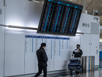 A travellers stands under a flight information display board inside Terminal 1 at Hong Kong International Airport on December 14, 2022 in Ho...