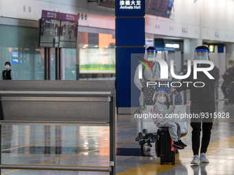 A girl, a woman and a man with luggages wearing a face shield at the arrival hall inside Terminal 1 at Hong Kong International Airport on De...