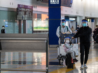 A girl, a woman and a man with luggages wearing a face shield at the arrival hall inside Terminal 1 at Hong Kong International Airport on De...