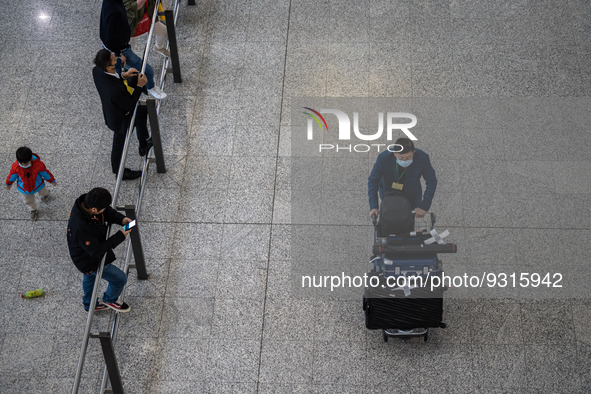 A man pushing a luggage trolley at the arrival hall inside Terminal 1 at Hong Kong International Airport on December 14, 2022 in Hong Kong,...