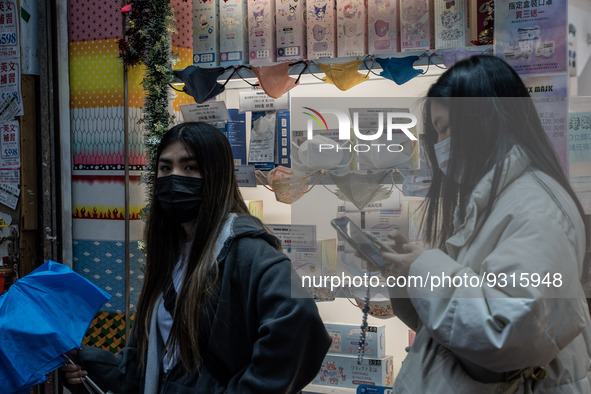 People walking pass a store selling face masks on December 14, 2022 in Hong Kong, China. The Hong Kong Government announced yesterday at a P...