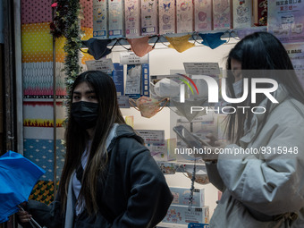 People walking pass a store selling face masks on December 14, 2022 in Hong Kong, China. The Hong Kong Government announced yesterday at a P...