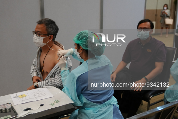 A health worker administers the COVID-19 vaccine to people at vaccination site inside the shopping mall in Bangkok on December 20, 2022 in B...