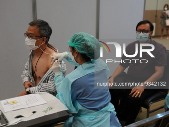 A health worker administers the COVID-19 vaccine to people at vaccination site inside the shopping mall in Bangkok on December 20, 2022 in B...