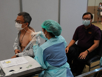 A health worker administers the COVID-19 vaccine to people at vaccination site inside the shopping mall in Bangkok on December 20, 2022 in B...