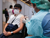 A health worker administers the COVID-19 vaccine to people at vaccination site inside the shopping mall in Bangkok on December 20, 2022 in B...