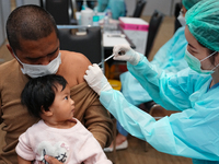 A health worker administers the COVID-19 vaccine to people at vaccination site inside the shopping mall in Bangkok on December 20, 2022 in B...