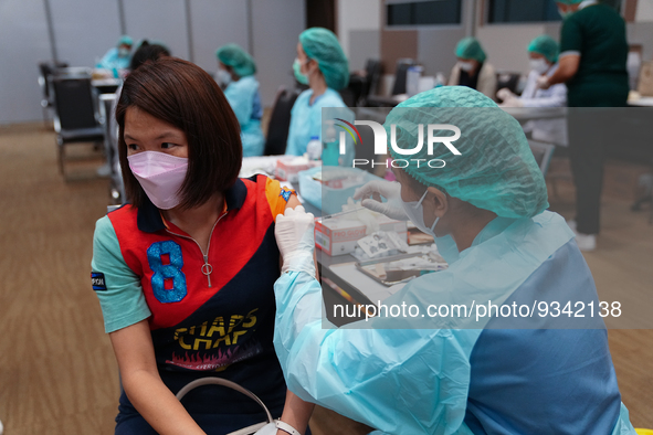 A health worker administers the COVID-19 vaccine to people at vaccination site inside the shopping mall in Bangkok on December 20, 2022 in B...