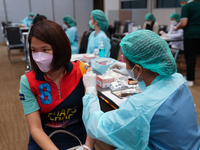 A health worker administers the COVID-19 vaccine to people at vaccination site inside the shopping mall in Bangkok on December 20, 2022 in B...