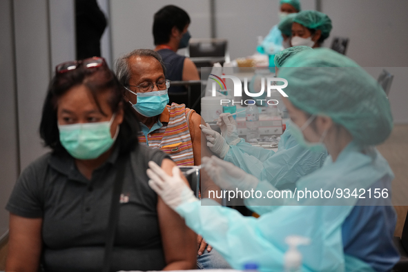 A health worker administers the COVID-19 vaccine to people at vaccination site inside the shopping mall in Bangkok on December 20, 2022 in B...