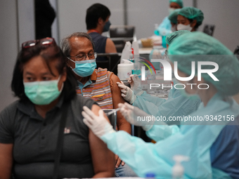 A health worker administers the COVID-19 vaccine to people at vaccination site inside the shopping mall in Bangkok on December 20, 2022 in B...