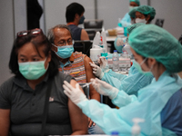 A health worker administers the COVID-19 vaccine to people at vaccination site inside the shopping mall in Bangkok on December 20, 2022 in B...