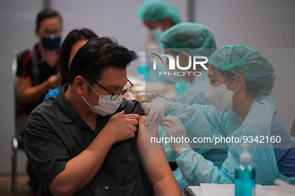 A health worker administers the COVID-19 vaccine to people at vaccination site inside the shopping mall in Bangkok on December 20, 2022 in B...