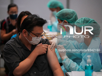 A health worker administers the COVID-19 vaccine to people at vaccination site inside the shopping mall in Bangkok on December 20, 2022 in B...