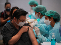 A health worker administers the COVID-19 vaccine to people at vaccination site inside the shopping mall in Bangkok on December 20, 2022 in B...