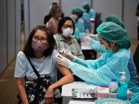 A health worker administers the COVID-19 vaccine to people at vaccination site inside the shopping mall in Bangkok on December 20, 2022 in B...