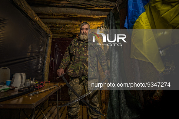 A soldier of a cossack battalion shows a couple of the ceremonial swords in the underground base of his unit near the frontlines of Zaporizh...