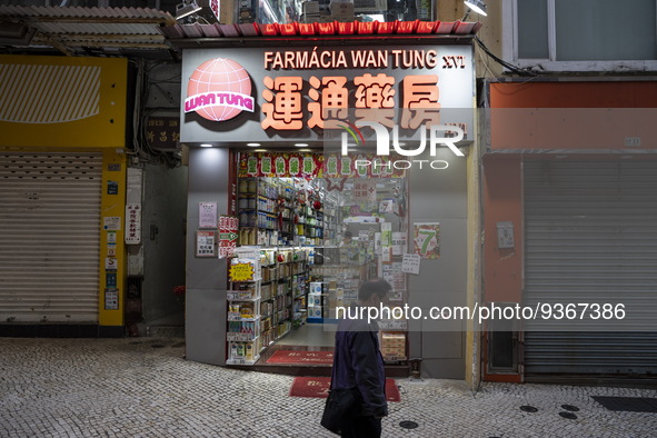 A man walks pass an open pharmacy store next to closed stores on December 29, 2022 in Macau, China. 