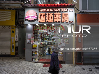 A man walks pass an open pharmacy store next to closed stores on December 29, 2022 in Macau, China. (