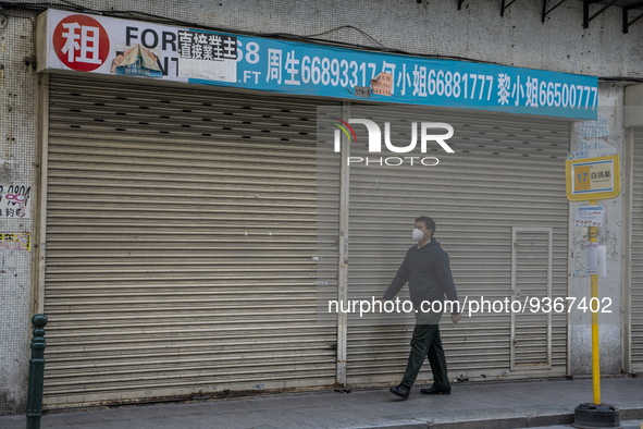 A man wearing a face mask walks pass a closed store on December 29, 2022 in Macau, China. 