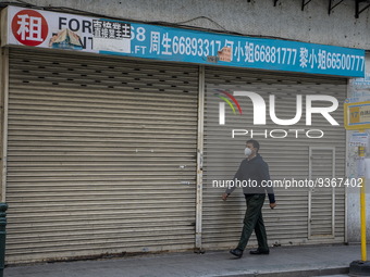 A man wearing a face mask walks pass a closed store on December 29, 2022 in Macau, China. (