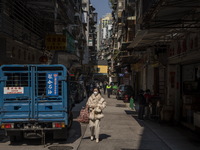 A women wearing a face mask walks downs a street on December 29, 2022 in Macau, China. (