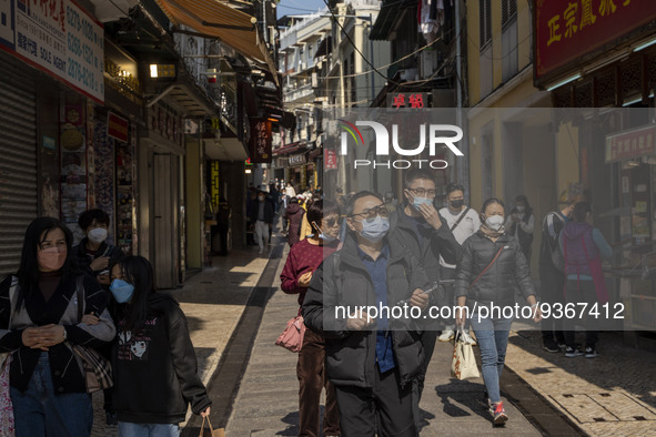 People wearing face masks walking in a street at a popular tourist district on December 29, 2022 in Macau, China. 