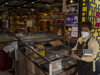 A worker wearing a face mask putting trays on a display counter at a food souvenir store on December 29, 2022 in Macau, China. (