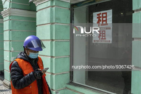 A Delivery worker wearing a face mask looks at his phone while walking pass a for rent sign on a window at an empty store on December 29, 20...