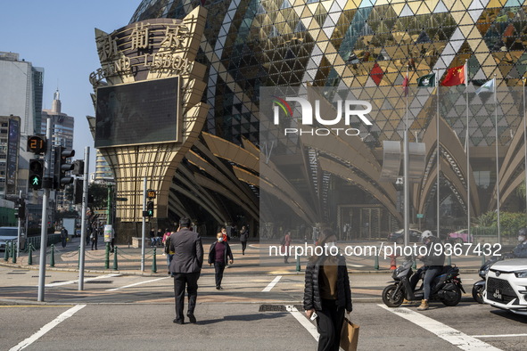 Pedestrian wearing face masks walks pass a street in front of the Grand Lisboa Hotel on December 29, 2022 in Macau, China. 