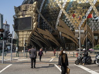 Pedestrian wearing face masks walks pass a street in front of the Grand Lisboa Hotel on December 29, 2022 in Macau, China. (