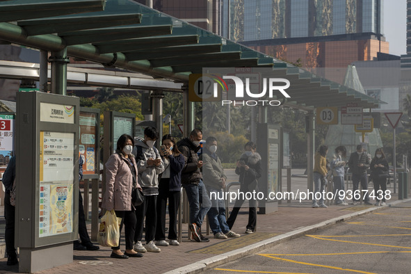 Commuters wearing face masks while waiting for a bus at a bus stop on December 29, 2022 in Macau, China. 