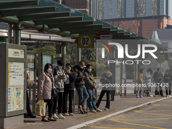 Commuters wearing face masks while waiting for a bus at a bus stop on December 29, 2022 in Macau, China. (