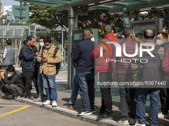 Commuters wearing face masks while waiting for a bus at a bus stop on December 29, 2022 in Macau, China. (