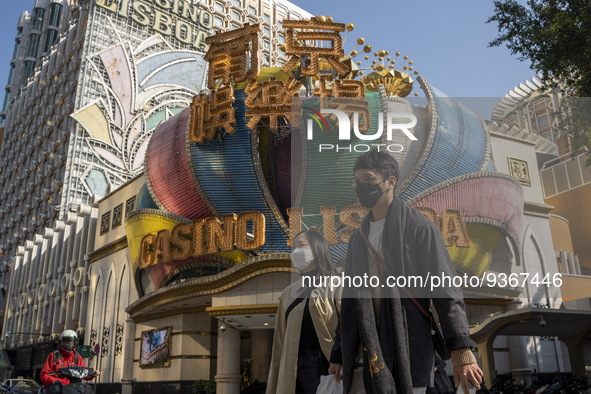 People wearing face masks walks pass the Casino Lisboa on December 29, 2022 in Macau, China. 