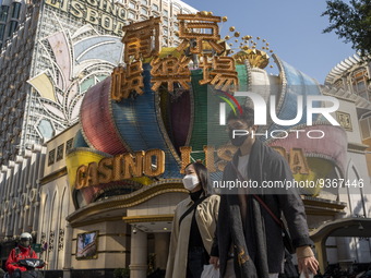 People wearing face masks walks pass the Casino Lisboa on December 29, 2022 in Macau, China. (