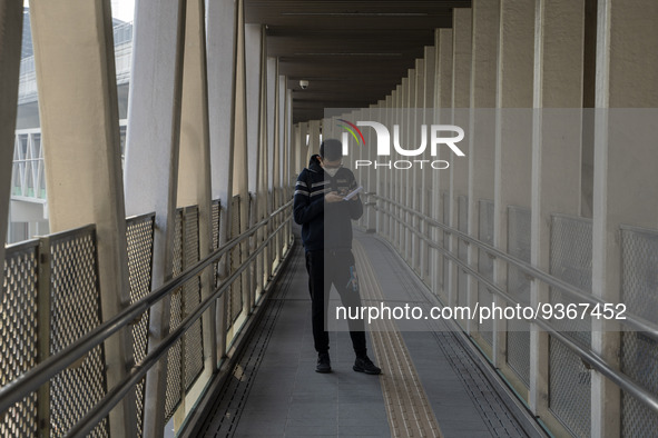 A man wearing a face mask looks at his phone while standing on a footbridge on December 29, 2022 in Macau, China. 