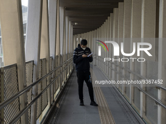 A man wearing a face mask looks at his phone while standing on a footbridge on December 29, 2022 in Macau, China. (